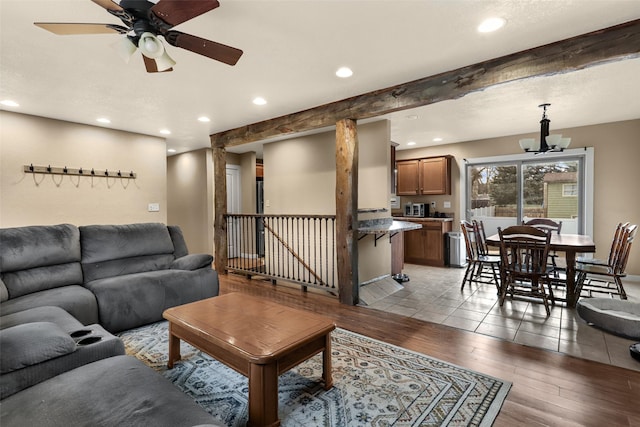 living area featuring recessed lighting, beam ceiling, ceiling fan with notable chandelier, and light wood finished floors