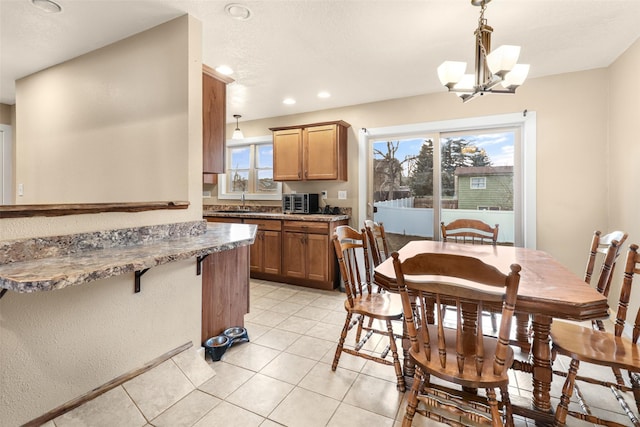 kitchen featuring hanging light fixtures, a notable chandelier, brown cabinetry, and light tile patterned floors