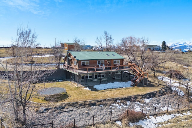 rear view of property with a lawn, a deck, fence, stairway, and metal roof