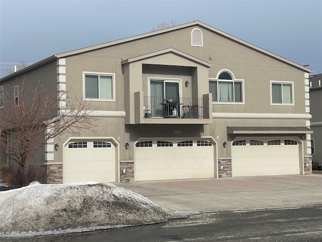 view of front of property featuring a balcony, stone siding, stucco siding, and a garage