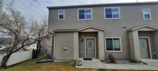 view of front facade featuring a front lawn, fence, and stucco siding