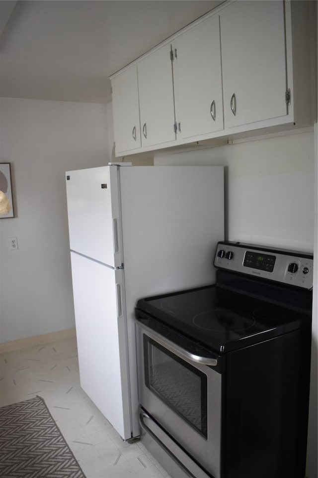 kitchen featuring baseboards, stainless steel range with electric stovetop, and white cabinetry