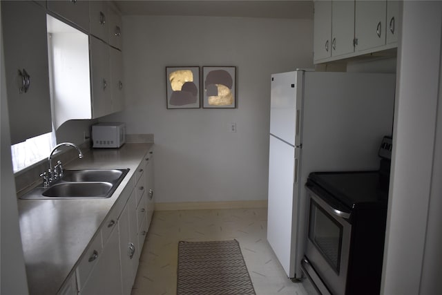 kitchen featuring stainless steel electric range oven, white microwave, a sink, light countertops, and white cabinetry