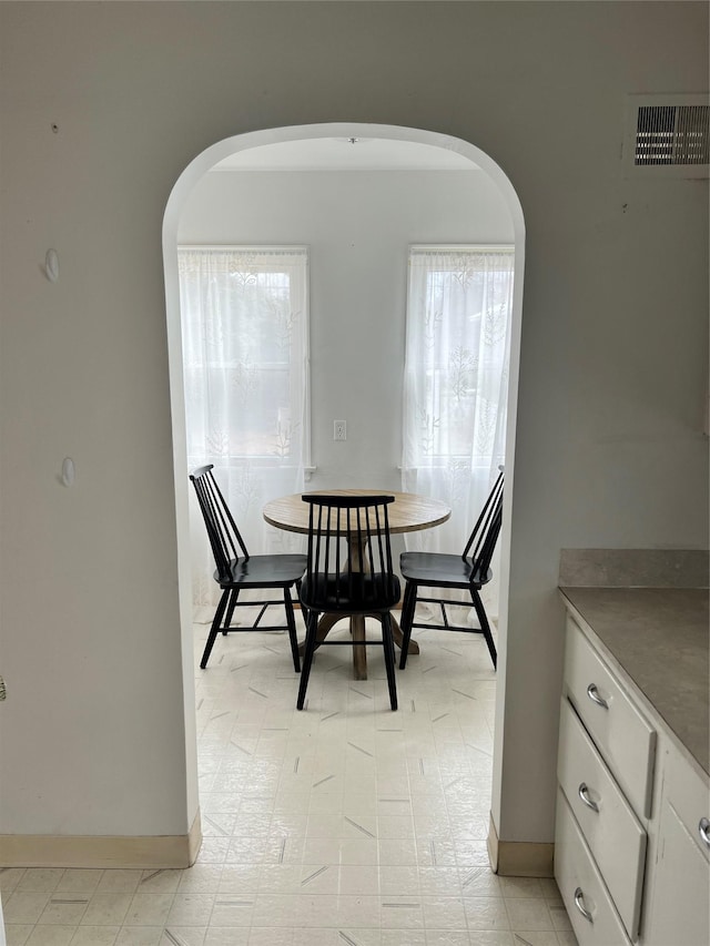 dining space featuring arched walkways, visible vents, and baseboards