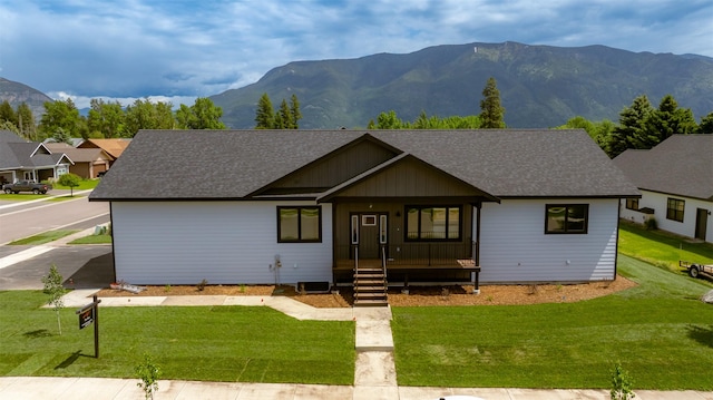 57 Hidden Cedar Loop, Columbia Falls, MT 59912 - view of front of property with a shingled roof, covered porch, a mountain view, and a front lawn