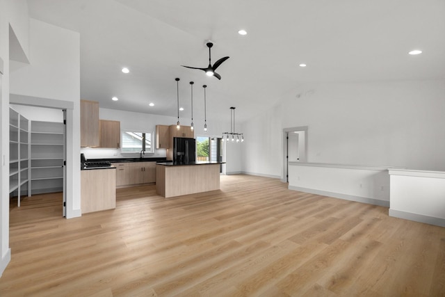 57 Hidden Cedar Loop, Columbia Falls, MT 59912 - kitchen with black fridge, a kitchen island, open floor plan, light brown cabinets, and vaulted ceiling