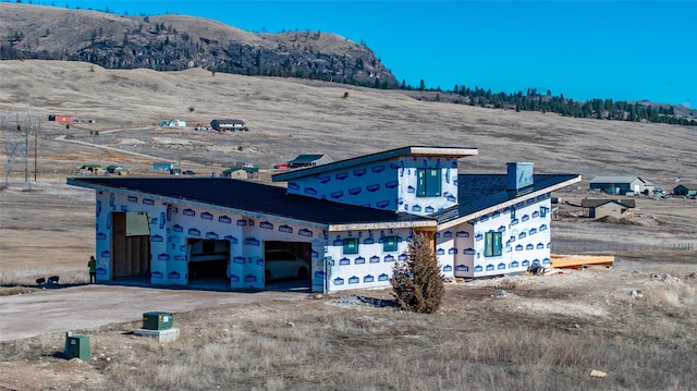 view of front of house featuring a garage, a mountain view, and dirt driveway