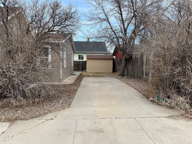 view of side of home featuring a storage shed, an outdoor structure, fence, and a chimney