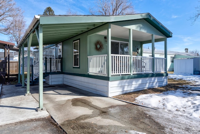 view of front of property featuring an attached carport, concrete driveway, and a porch