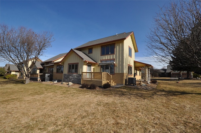 back of house with a yard, stone siding, and roof with shingles