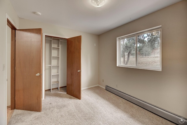 unfurnished bedroom with carpet, a closet, baseboard heating, and baseboards