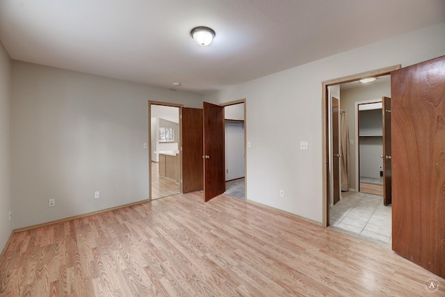 unfurnished bedroom featuring a spacious closet and light wood finished floors