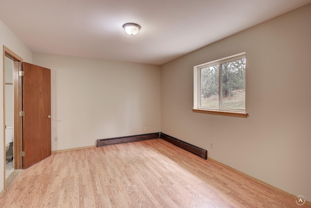 spare room featuring wood finished floors and a baseboard radiator