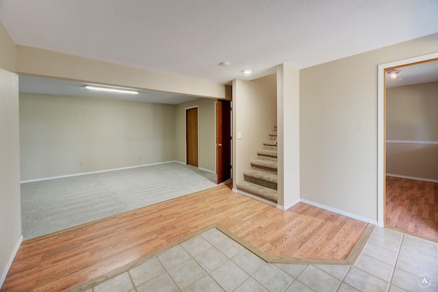 unfurnished room with stairway, baseboards, and light wood-type flooring