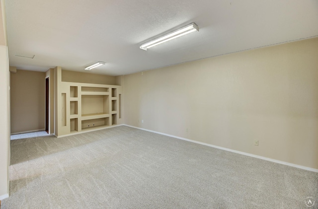 unfurnished room with built in features, baseboards, and light carpet