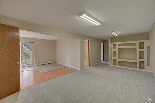 carpeted spare room featuring built in shelves, baseboards, and baseboard heating