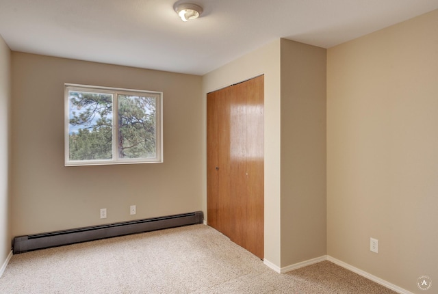 carpeted empty room featuring a baseboard heating unit and baseboards