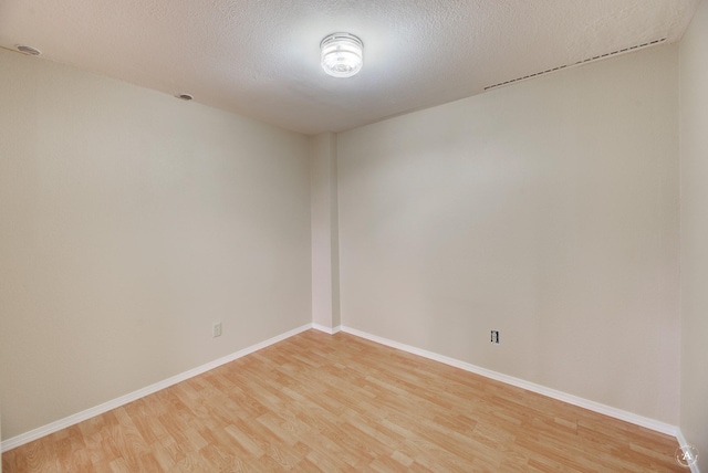 unfurnished room with a textured ceiling, baseboards, and light wood-style floors