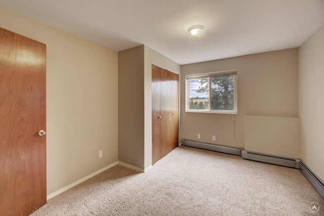 unfurnished bedroom with a baseboard heating unit, a closet, baseboards, and carpet floors