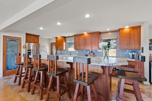 kitchen featuring decorative backsplash, plenty of natural light, recessed lighting, and stainless steel refrigerator with ice dispenser