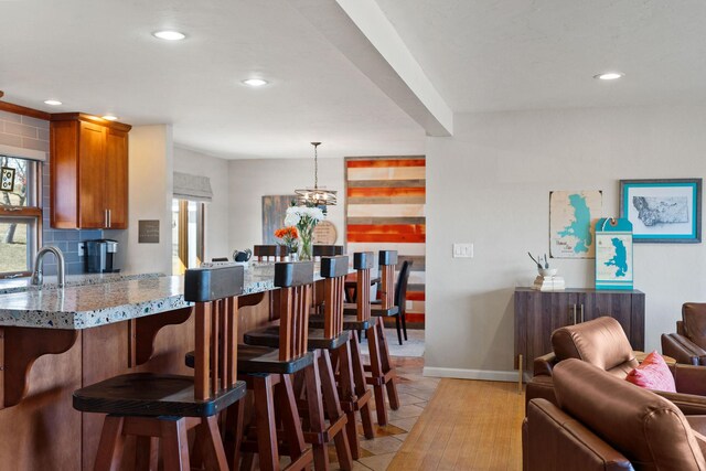 128 Sunset Rdg, Lakeside, MT 59922 - kitchen with brown cabinetry, a breakfast bar, open floor plan, recessed lighting, and light stone countertops