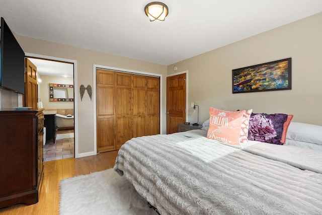 bedroom with a closet, light wood-style floors, and ensuite bath