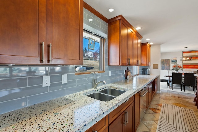 kitchen with a sink, light stone counters, tasteful backsplash, recessed lighting, and brown cabinetry