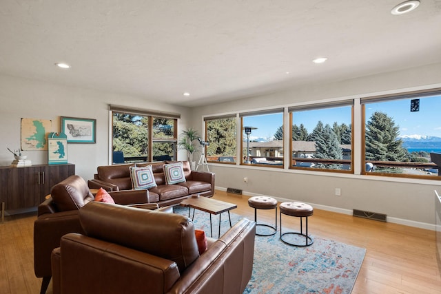 living area with recessed lighting, baseboards, visible vents, and light wood finished floors