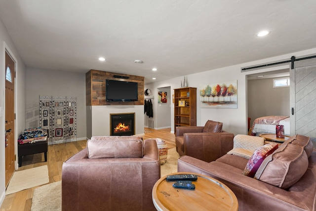 living area featuring wood finished floors, baseboards, recessed lighting, a barn door, and a large fireplace