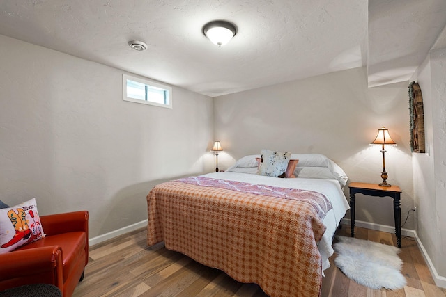 bedroom with baseboards and wood finished floors