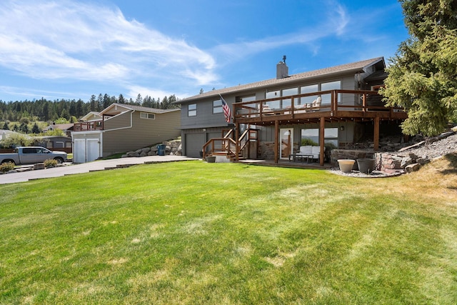128 Sunset Rdg, Lakeside, MT 59922 - rear view of house featuring an attached garage, a wooden deck, driveway, a chimney, and a lawn