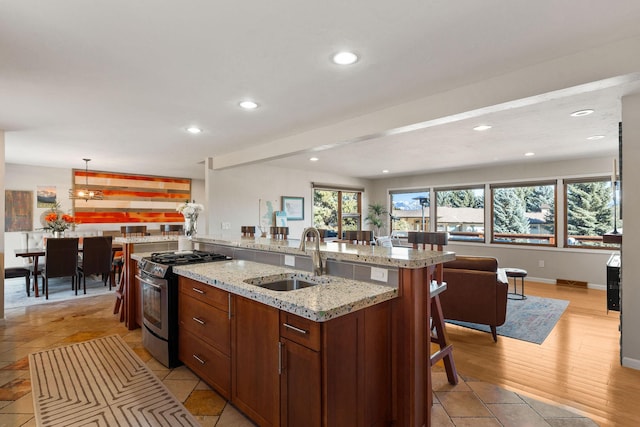 kitchen with gas stove, baseboards, recessed lighting, a sink, and a kitchen breakfast bar