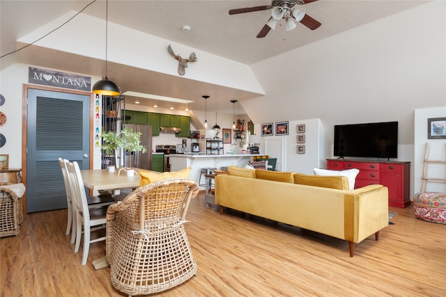 living room featuring ceiling fan, light wood-style floors, and vaulted ceiling