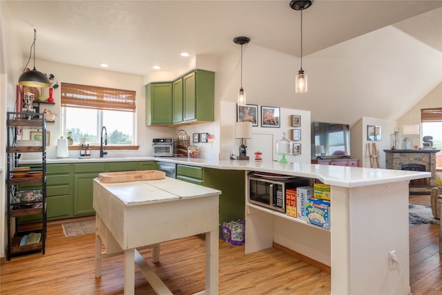 kitchen with light wood finished floors, a sink, a peninsula, and green cabinetry