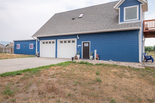 exterior space with a garage, concrete driveway, and roof with shingles