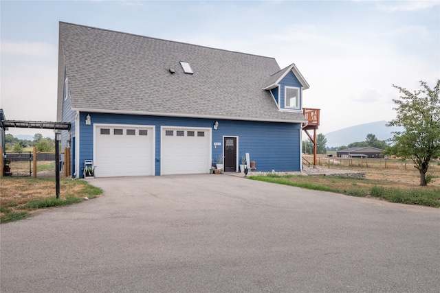 view of front facade with a garage, roof with shingles, and fence