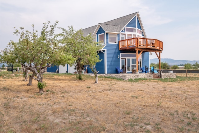 rear view of property with a patio, roof with shingles, and a deck