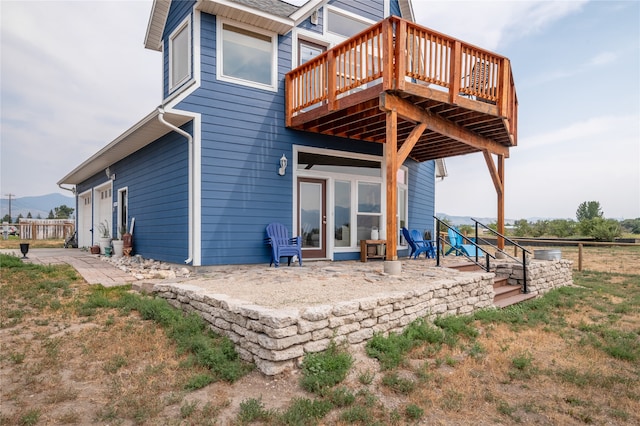 back of property with a wooden deck and a garage