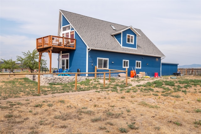 rear view of house with a deck and roof with shingles