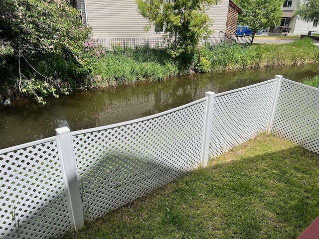 view of dock with a water view and fence