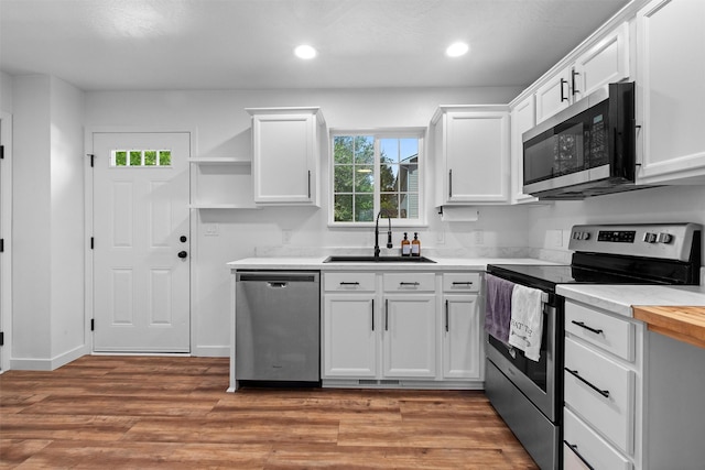 kitchen with light wood-style flooring, a sink, open shelves, white cabinetry, and stainless steel appliances