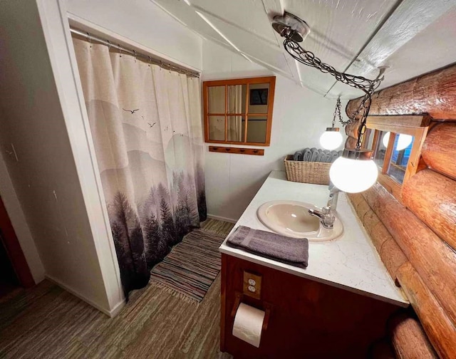 bathroom featuring vanity, wood finished floors, lofted ceiling, curtained shower, and rustic walls