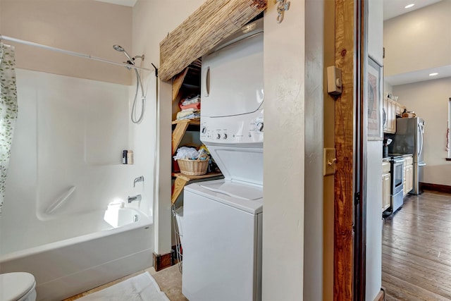 clothes washing area with stacked washer and dryer, hardwood / wood-style floors, recessed lighting, baseboards, and laundry area