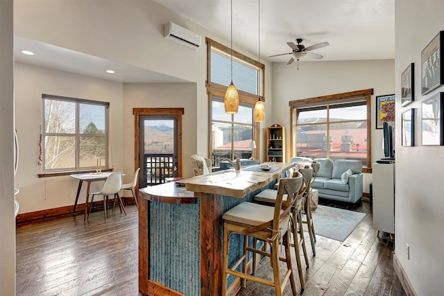 dining area featuring a wall unit AC, dark wood-type flooring, and a wealth of natural light