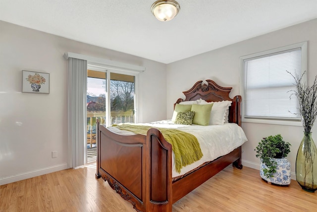 bedroom with access to exterior, light wood-type flooring, and baseboards