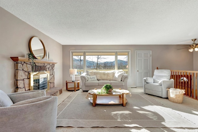 carpeted living area featuring a fireplace, a textured ceiling, and a ceiling fan