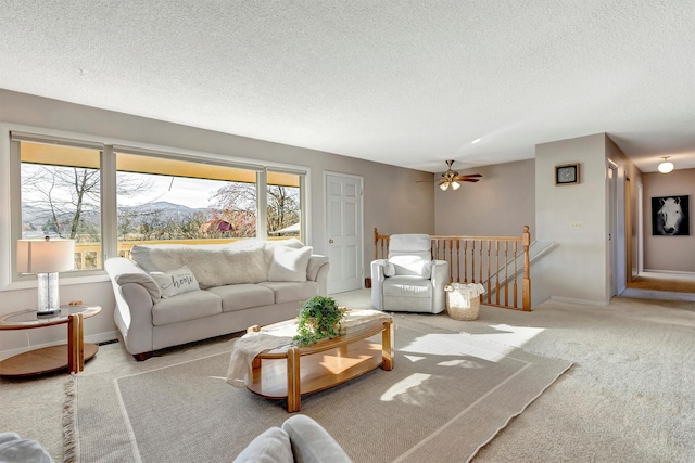 carpeted living room with a mountain view, baseboards, a textured ceiling, and ceiling fan