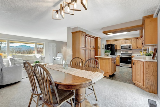 dining room with light colored carpet, visible vents, and a textured ceiling