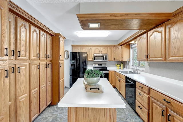 kitchen with a center island, light countertops, stone finish floor, black appliances, and a sink