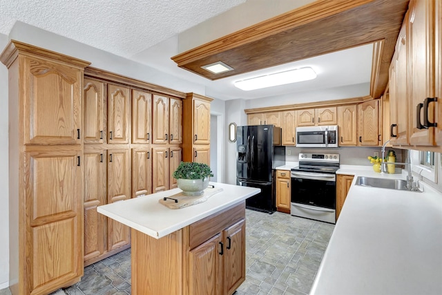 kitchen with a kitchen island, a sink, stainless steel appliances, light countertops, and a textured ceiling